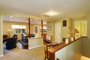 A spacious living area with a dining table, chairs, and a sofa. There is a staircase leading to an upper level.