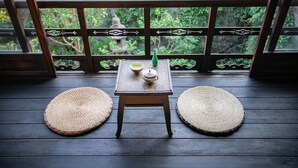 A small wooden table with a white teapot and a green bottle on a balcony with woven mats. - Higurashi-Sou (Kyoto)