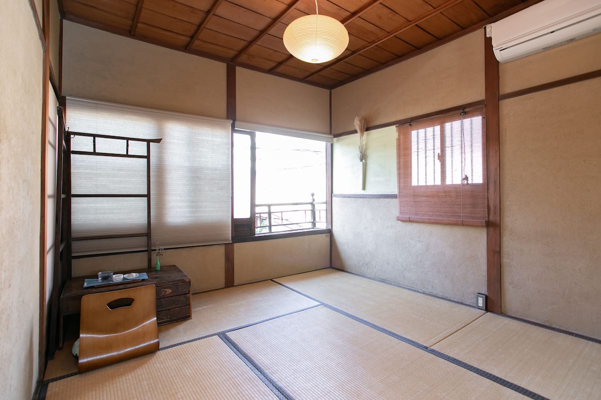 Ein traditioneller japanischer Raum mit Tatami-Böden, Schiebetüren und einer niedrigen Holzbalkendecke.