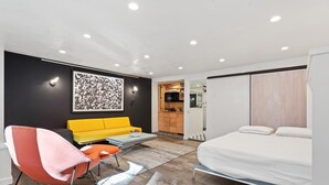 Et moderne hotelværelse med seng, sofa, stol, et tekøkken og et badeværelse.