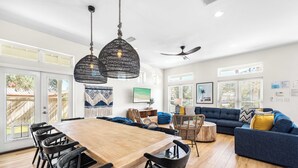 A spacious living area with a wooden dining table, black chairs, a blue sofa, and a ceiling fan.