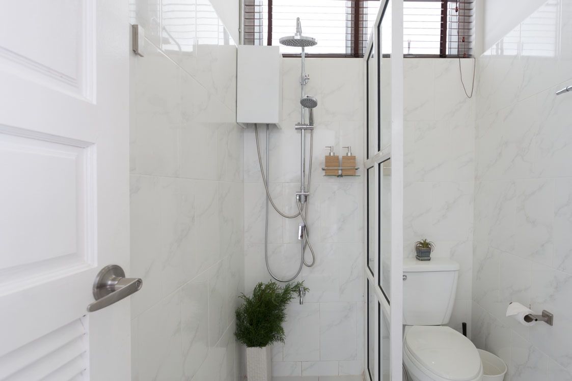 A modern bathroom with a shower, toilet, and a small plant.