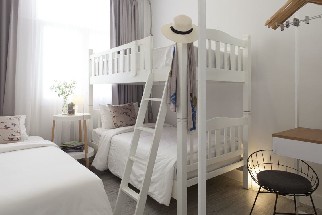 Habitación con literas, una mesita con lámpara y una silla.