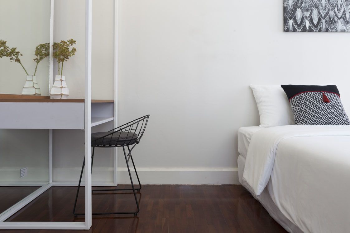A bedroom with a bed, a desk with a chair, and a mirror.