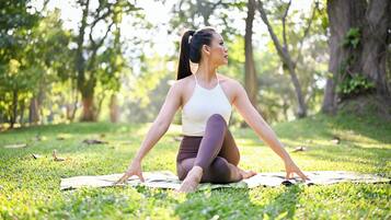 A person sitting on a mat outdoors, surrounded by trees.