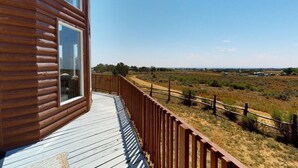 A wooden cabin with a deck overlooking a dry, open landscape. - Juniper Ridge 5 BR Family Cabin (Blanding)