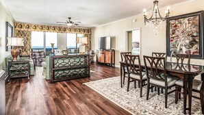 A spacious living room with a wooden floor, a dining area with a glass table, and a large window overlooking the ocean. - $150 activities - E-gift card when you book - Luxury, Oceanfront Retreat - 2 King Beds | M804 (Myrtle Beach)