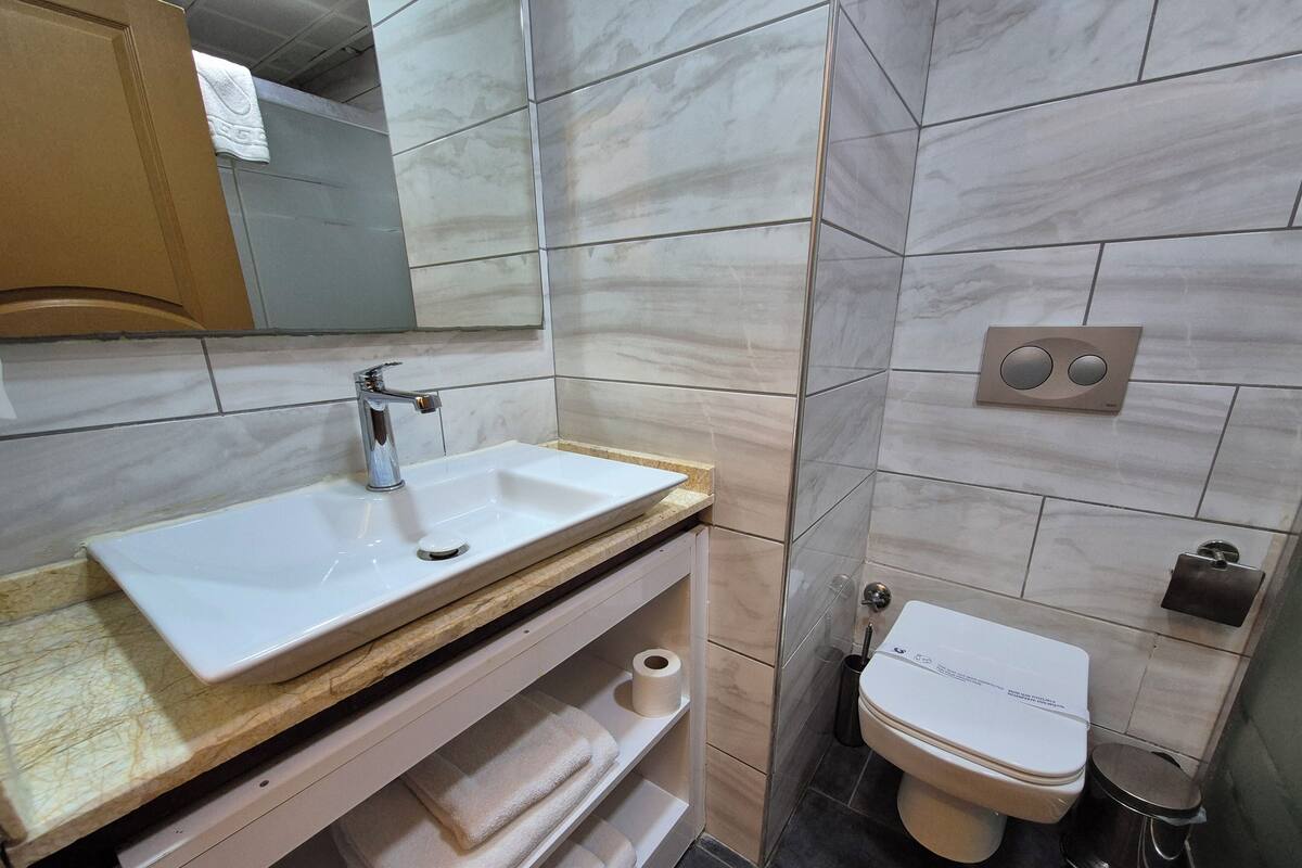 Ein Badezimmer mit Waschbecken, Spiegel, Toilette und Handtuchhalter.