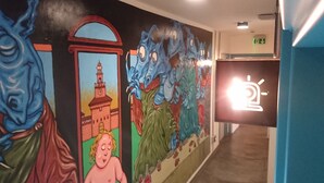 A hallway with colorful murals, including a clock tower and abstract figures. - Madama Hostel & Bistrot (Milan)