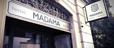 A hostel named MADAMA with a sign indicating it offers both hostel and bistro services.