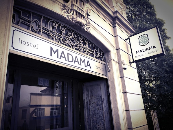 A hostel named MADAMA with a sign indicating it offers both hostel and bistro services.