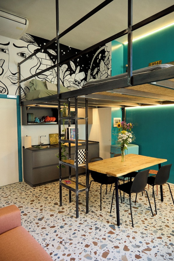 Un espacio habitable compacto con literas, kitchenette y una zona de comedor con sillas.
