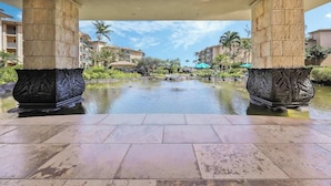 A hotel lobby with a central water feature, stone columns, and surrounding greenery. - H206 Ocean View Suite - Modern and Clean - Sleeps 6 in Air Conditioned Comfort! (Kapaa)