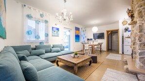 A living room with a sectional sofa, a wooden coffee table, and a dining area with a table and chairs. - Hacienda Babina, Island Cres, Lounge, Whirpool, Pool...Seaview (Miholascica)