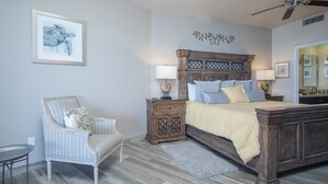 Una camera da letto con un letto in legno, due comodini, una sedia, una ventola a soffitto e un quadro appeso al muro.
