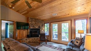 A cozy living room with a stone fireplace, leather sofas, and a wooden ceiling. - Grand View - Mountain Views, Pool Table, Fire Pit (Banner Elk)