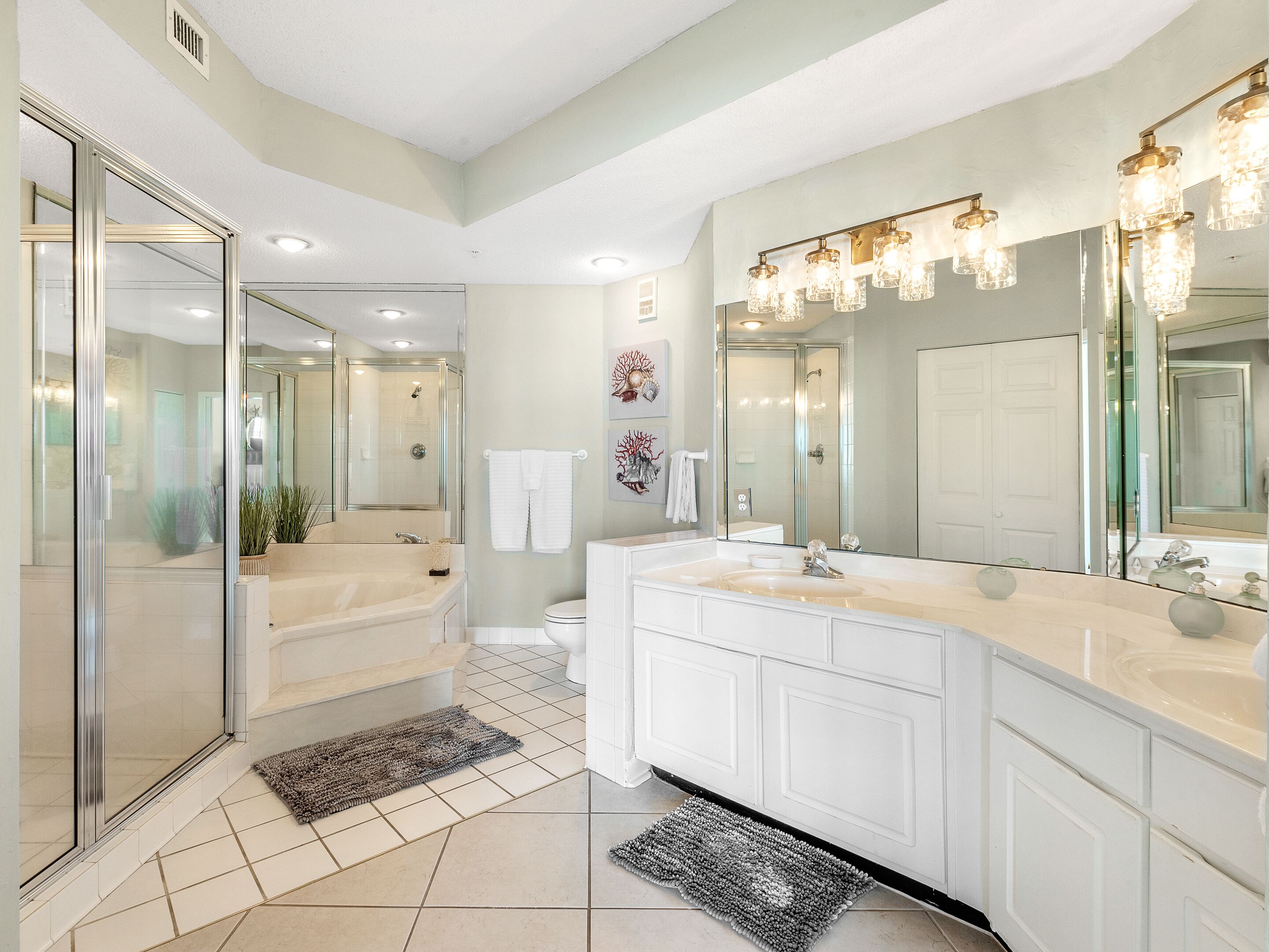 A modern bathroom with a glass-enclosed shower, a large vanity with a mirror, and a walk-in shower.