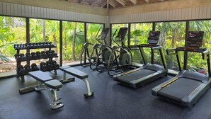 Une salle de sport équipée de tapis de course, de vélos elliptiques et d’haltères.