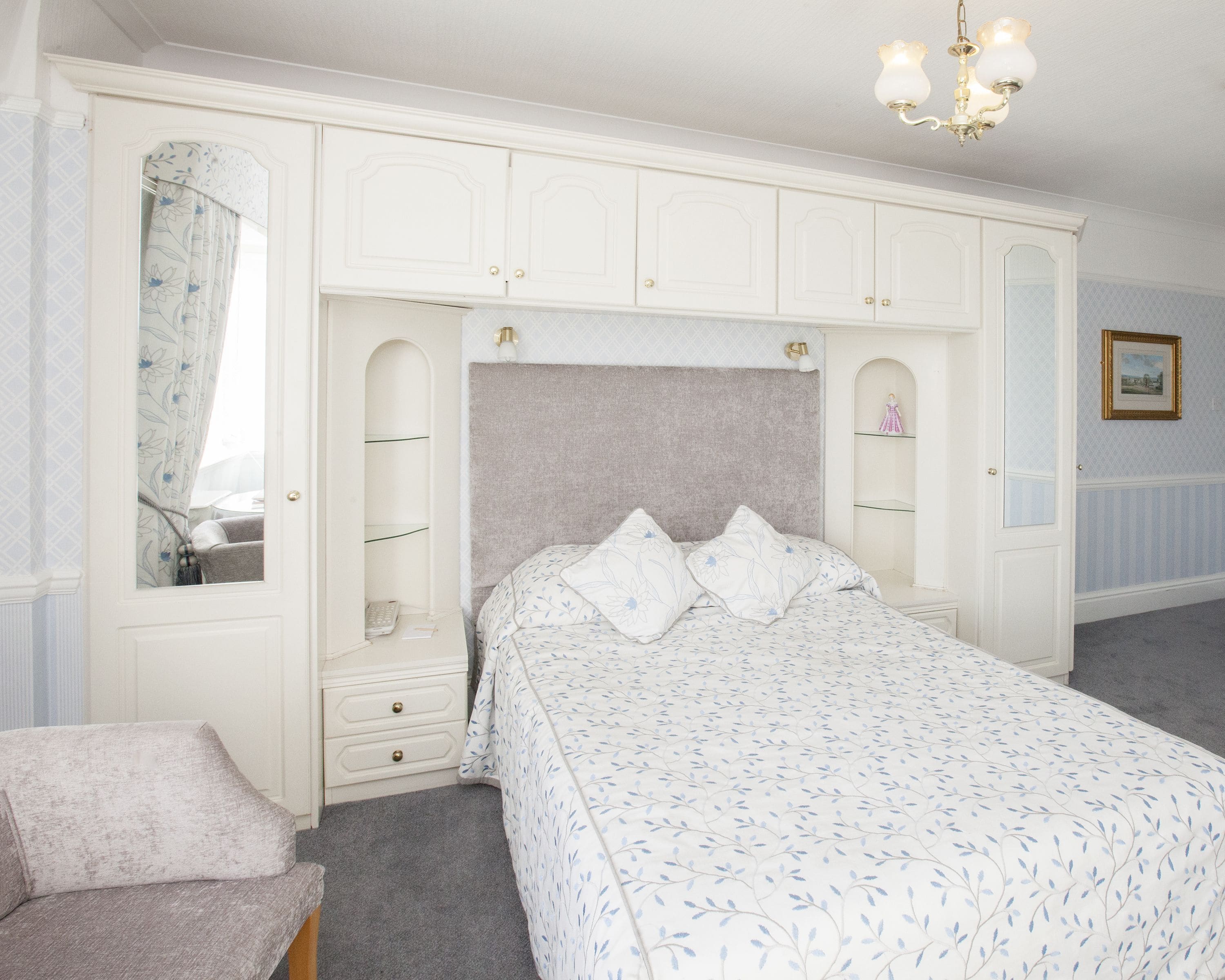 Une chambre à coucher avec un lit, une chaise, une armoire et un lustre.