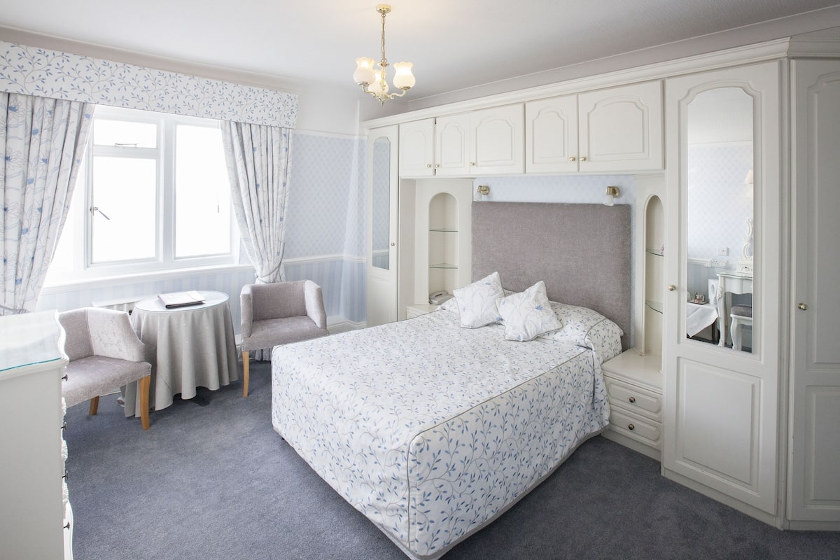 A bedroom with a bed, a desk, a chair, and a wardrobe.