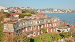 A coastal building with multiple stories, large windows, and a garden area. - The Livermead House (Torquay)