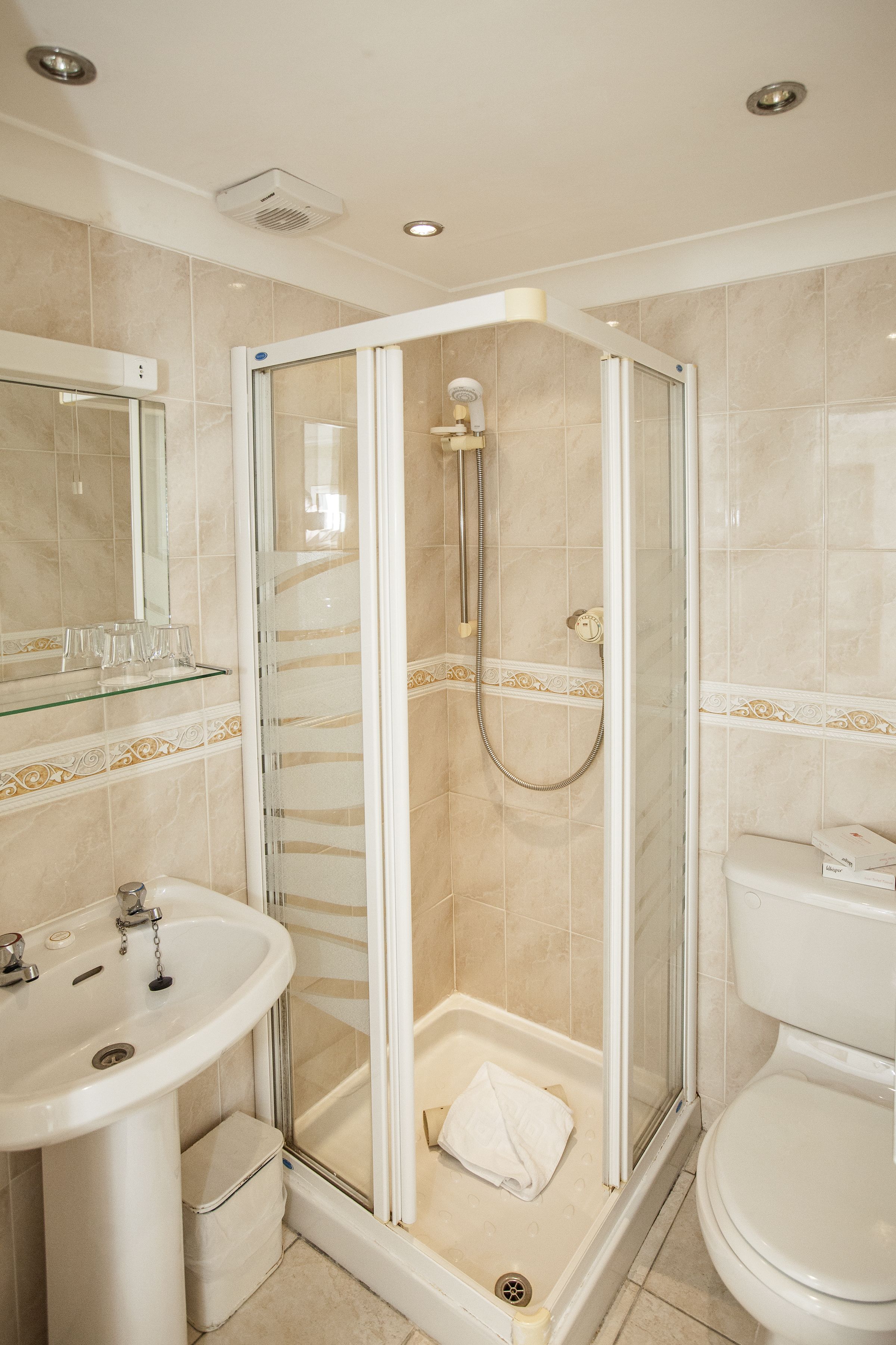 Un baño moderno con ducha acristalada, lavamanos pedestal y retrete.