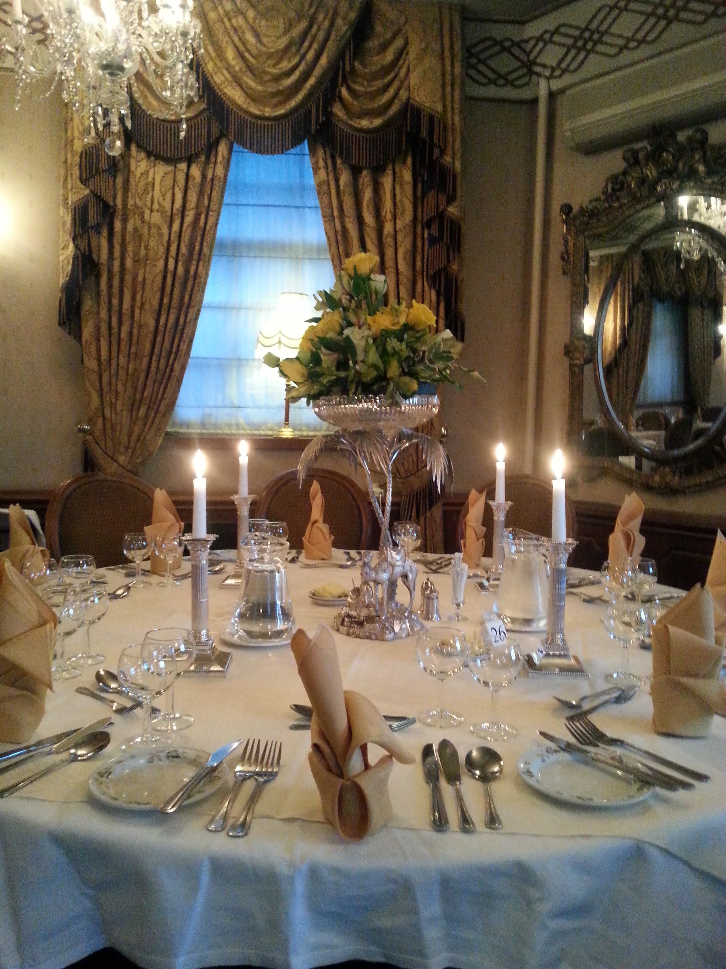 A formal dining table set with candles, silverware, and a centerpiece of yellow flowers.