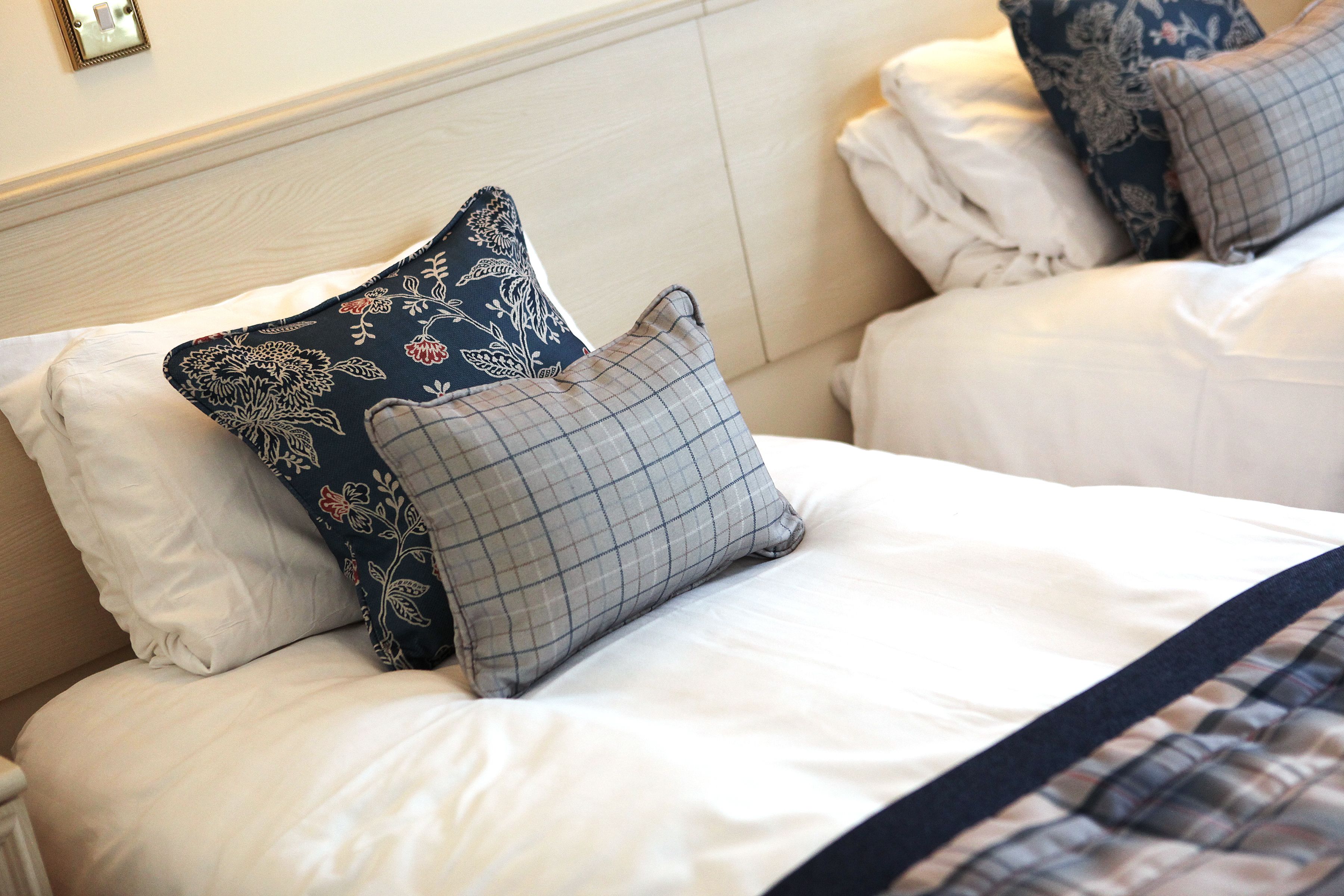 A hotel room with a neatly made bed, white bedding, and decorative pillows.