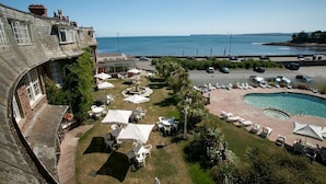 A courtyard with outdoor seating, a swimming pool, and a view of the sea. - The Livermead House (Torquay)