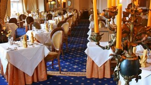 A formal dining room with tables set for service, chandeliers, and tall candles. - The Livermead House (Torquay)