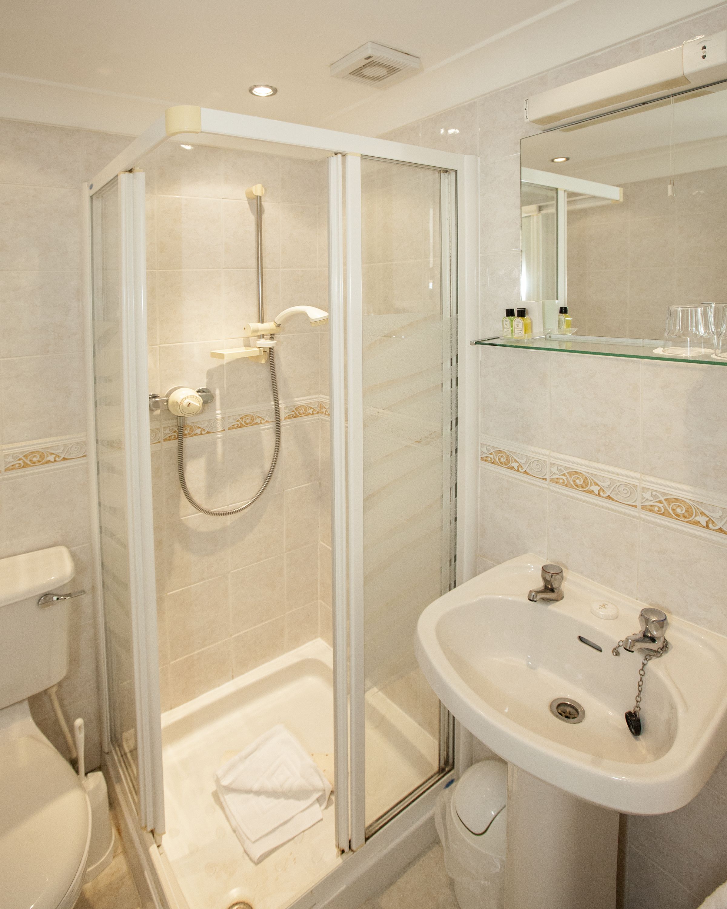 A modern bathroom with a glass-enclosed shower, a white sink, and a mirror above the sink.