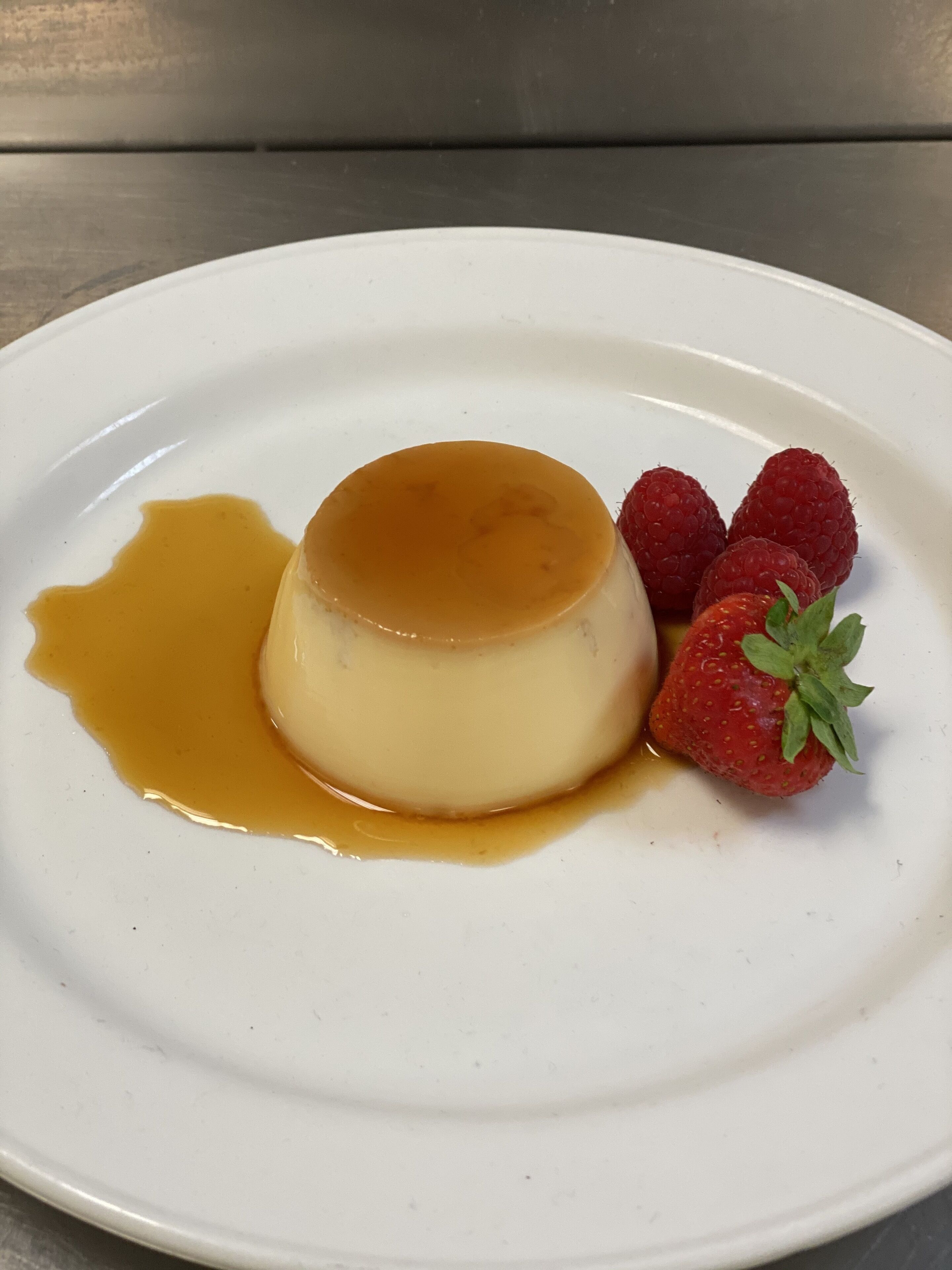 En dessert på en vit tallrik, serverad med karamellsås och jordgubbar.