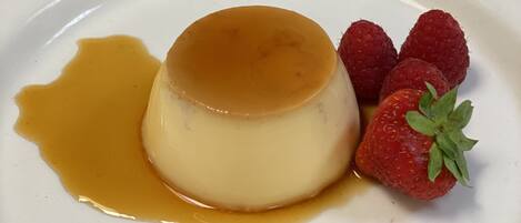 Un dessert servi dans une assiette blanche, nappé de sauce au caramel et garni de fraises.