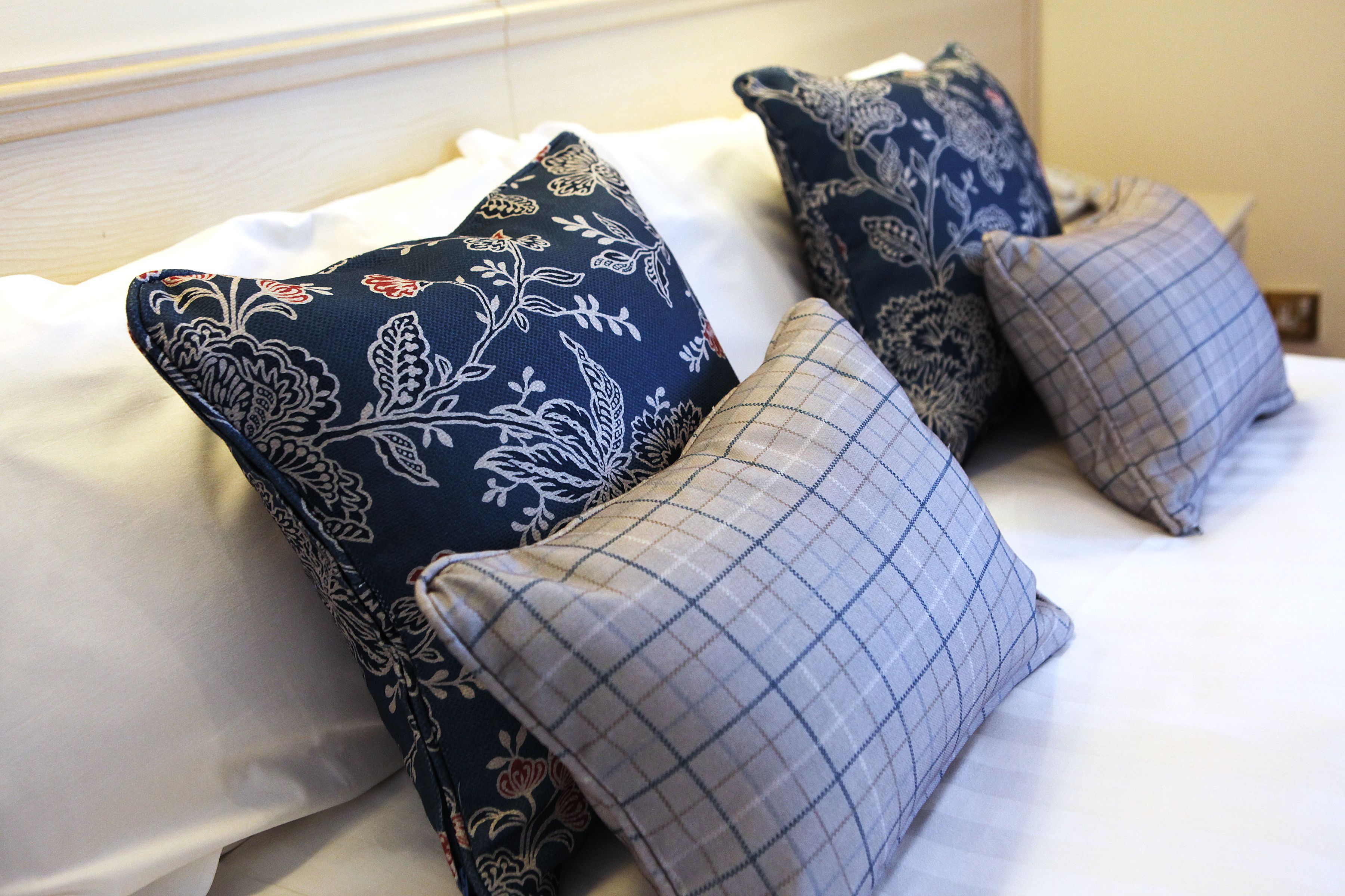 A bed with multiple pillows, including floral and checkered patterns.