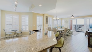 A spacious kitchen with a granite island, large windows with blinds, and a dining area with chairs and a table. - Picturesque Gulf Views from this 3BR Condo! (Orange Beach)