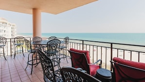 A balcony with outdoor seating, a view of the beach, and a building in the background. - Picturesque Gulf Views from this 3BR Condo! (Orange Beach)