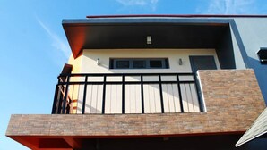 A modern building with a flat roof, a balcony with a metal railing, and a brick facade. - El Vistra Travellers Inn & Coffee Shop (Calumpit)