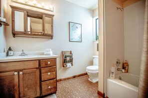 Un baño con tocador de madera, inodoro, bañera y ducha.