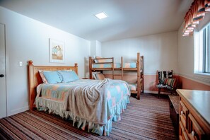 Un dormitorio con una cama grande, una litera, un aparador de madera y una silla.