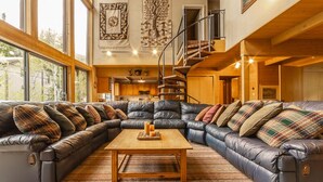 A spacious living room with a large leather sectional sofa, a wooden coffee table, and a staircase leading to an upper level. - Storm Mountain Escape by Cottonwood Lodging (Brighton)