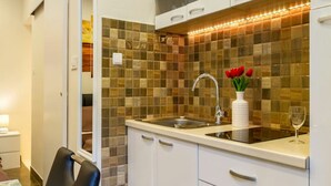 Una cocina moderna con salpicadero de azulejos, un lavamanos de acero inoxidable y muebles de cocina blancos.
