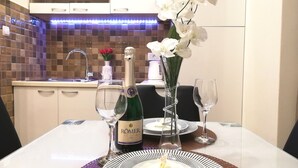Una mesa de comedor con una botella de RÖMER champagne, dos copas de vino, un jarrón con orquídeas blancas y un plato con un centro floral.