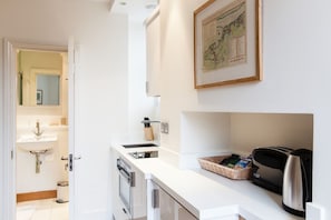 Una cocina moderna con encimera blanca, cafetera y una cesta de pan.