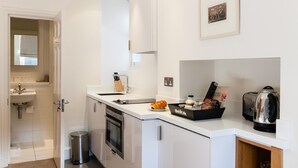 Una cocina moderna con encimera blanca, electrodomésticos de acero inoxidable y un pequeño cubo de basura.