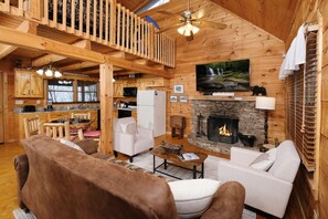 Interior acogedor de una cabaña con chimenea, muebles de madera y un televisor montado en la pared.