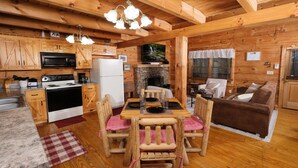 Interior de una cabaña de madera con cocina, comedor y sala de estar.