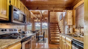 A wooden cabin kitchen with a central island, built-in microwave, stove, and dishwasher.