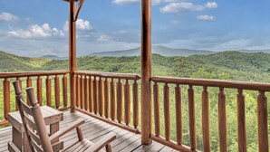 A wooden deck with a view of a forested mountain range.