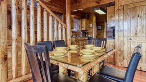 A wooden interior with a dining table set for six, surrounded by chairs.