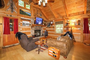 A log cabin interior with a fireplace, wooden furniture, a television, and various decorations.